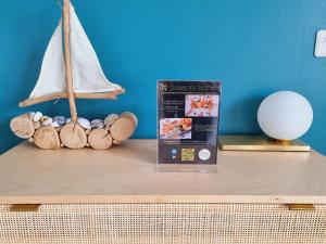 a book and a toy sailboat on a table at Sainte Cécile: appartement 2ch 6/7 pers in Camiers