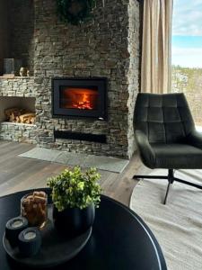 ein Wohnzimmer mit Kamin und einem Stuhl und einem Tisch in der Unterkunft Brand new cabin on the sunny side of Gaustatoppen with a beautiful view in Tuddal