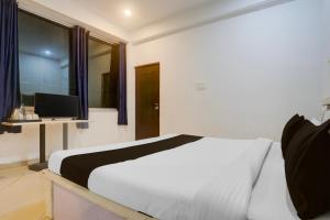 sypialnia z białym łóżkiem i telewizorem w obiekcie Hotel O The Hunger Byte Resort w mieście Bodh Gaja