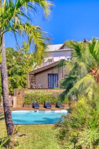 eine Villa mit Swimmingpool und Palmen in der Unterkunft Villa Romeo in L’Étang-Salé