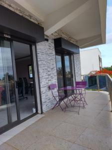 Dos sillas moradas en un patio exterior de un edificio. en Résidence DELIA, en Antsiranana