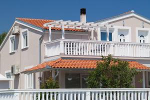ein weißes Haus mit einem Balkon und einem weißen Zaun in der Unterkunft Moderne Ferienwohnung mit jacuzzi in Ližnjan