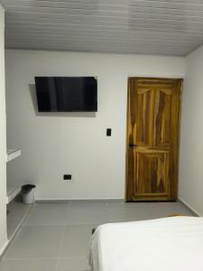 a bedroom with a bed and a wooden door at Hotel coral Issa in Bahía Solano