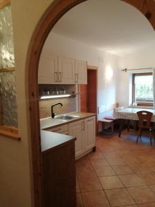 a kitchen with an arch over a sink and a table at Pension Ferienwohnungen Marchnerhof in Terento