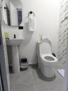 a white bathroom with a toilet and a sink at Hotel coral Issa in Bahía Solano