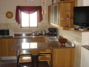 eine Küche mit Spüle und Theke mit Hockern in der Unterkunft Kleines Ferienhaus mit eigener, teils überdachter Terrasse in Alcalá