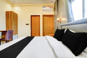 a bedroom with a large white bed with black pillows at Hotel O Fortune Palace in Hinjewadi
