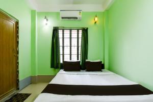 a bedroom with a bed with green walls and a window at Hotel O Sampad in Baharampur
