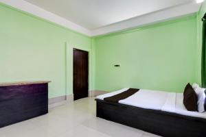 a bedroom with a bed in a room with green walls at Hotel O Sampad in Baharampur