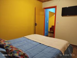 een slaapkamer met een bed en een flatscreen-tv bij Chalé Emília Costa in Ouro Preto