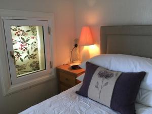 1 dormitorio con cama, lámpara y ventana en Ronas House, en Inverness