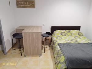 a bedroom with a bed and a desk and two stools at Studio Le Yuka entre Mer et Montagne in Villelongue-dels-Monts