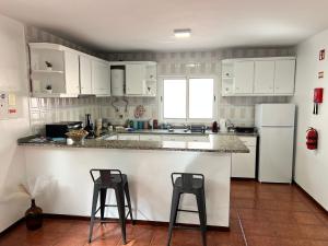 une cuisine avec des placards blancs et deux tabourets de bar dans l'établissement Meu Quintal Apartaments 1, Calheta Madeira, à Calheta