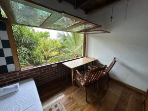 a table and two chairs in a room with a large window at Verdant Hill Villa in Tangalle