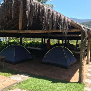 zwei blaue Zelte unter einem Strohdach in der Unterkunft Camping Refugio SacodoCeu2026 in Saco do Ceu