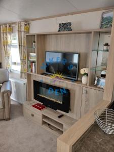 a living room with a tv and a entertainment center at Hikers Den, Brigham, Cockermouth, Cumbria in Cockermouth