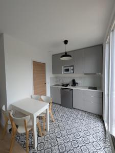 - une cuisine avec une table et des chaises blanches dans la chambre dans l'établissement Maison Le cottage, à Crosne