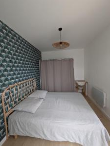 une chambre avec un lit avec un mur bleu dans l'établissement Maison Le cottage, à Crosne