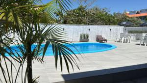 a swimming pool with a palm tree next to it at Pousada Kauai in Imbituba