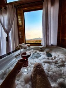a person holding a glass of wine in a bath tub at Cabanas Céu e Mel - Cabana 01 in Bom Retiro +19 photos