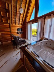 a large tub in a room with a large window at Cabanas Céu e Mel - Cabana 01 in Bom Retiro