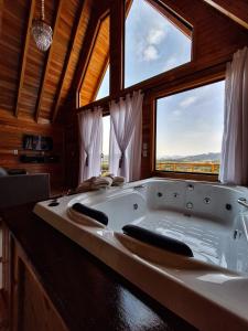 a large white bath tub in a room with windows at Cabanas Céu e Mel - Cabana 01 in Bom Retiro