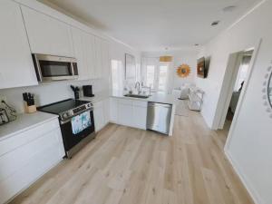 Starfish Room #1 في Pass Christian: مطبخ بدولاب بيضاء وأرضية خشبية