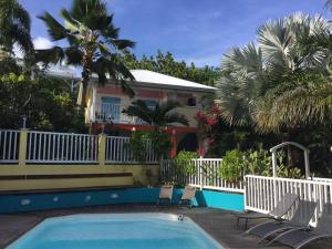 a pool in front of a house with palm trees at bungalow ti dauphin rdc in Sainte-Anne