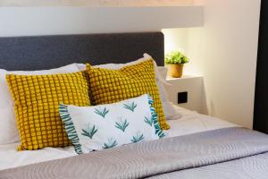 a bed with yellow and white pillows on it at Suite Cigale Jaune avec terrasse et piscine à Antibes in Antibes