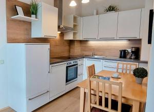 eine Küche mit weißen Schränken und einem Holztisch in der Unterkunft Appartements Romanin in Pörtschach am Wörthersee