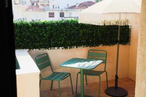 a table and two chairs and an umbrella on a balcony at Suite Cigale Jaune avec terrasse et piscine à Antibes in Antibes