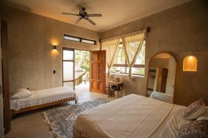 a bedroom with two beds and a ceiling fan at La Posada del Sol Boutique Hotel Tulum in Tulum