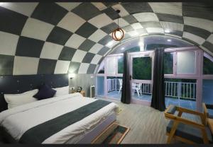 Un dormitorio con una cama grande en una habitación con techo de tablero de ajedrez. en The Lush Pods, en Jāmb