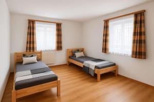una habitación con dos camas y dos ventanas en Ferienwohnung Eichhorner, en Außervillgraten