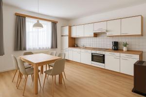 Una cocina con gabinetes blancos y una mesa y sillas. en Ferienwohnung Eichhorner, en Außervillgraten