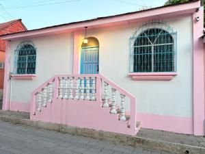 a pink and white building with a pink door and stairs at Casa Azucena in Flores