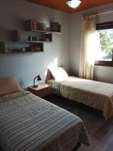 ein Schlafzimmer mit zwei Betten und einem Fenster in der Unterkunft A Casa Amarela - Morada dos Maçaricos - Tranquilidade próxima ao mar in Balneário Gaivotas