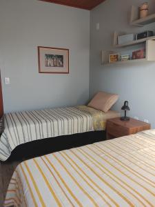 una camera con due letti, un tavolo e scaffali di A Casa Amarela - Morada dos Maçaricos - Tranquilidade próxima ao mar a Balneário Gaivotas