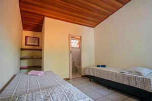 a bedroom with two beds and a wooden ceiling at Casa em condomínio com piscina in Paraty +24 photos