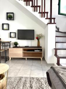 a living room with a tv and a staircase at Vega Maspalomas - Escapada de sol, piscina y relax in San Bartolomé