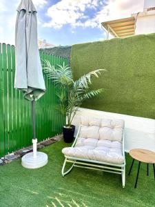 a patio with a white couch and an umbrella at Vega Maspalomas - Escapada de sol, piscina y relax in San Bartolomé