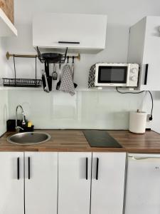 a white kitchen with a sink and a microwave at Vega Maspalomas - Escapada de sol, piscina y relax in San Bartolomé