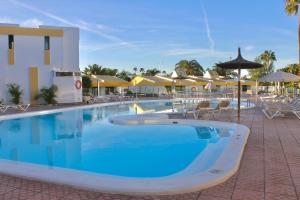 a large pool with chairs and umbrellas in a resort at Vega Maspalomas - Escapada de sol, piscina y relax in San Bartolomé