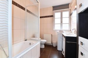 a bathroom with a tub and a toilet and a sink at Maison de ville le Cocon d Alsace - garage inclus in Ribeauvillé