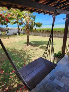 a hammock in a yard with a palm tree at Espaço Varanda e Mar in São Miguel do Gostoso