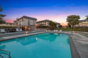 a swimming pool with chairs and a building in the background at Ocean Breeze Getaway - Solana Beach Condo in Solana Beach