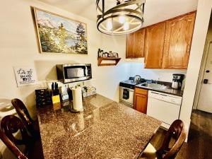una cucina con tavolo, forno a microonde e piano cottura di Sierra Pines Condo - Inside Yosemite - Sleeps 4 a Yosemite West Altre 4 foto