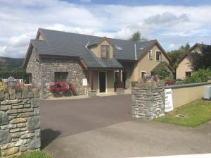 a house with a stone wall and a driveway at Golf Course View in Kenmare