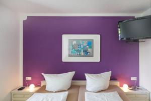 a room with two beds and a purple wall at Pension Sieg in Rust