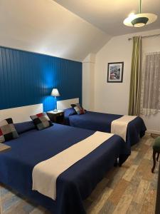 deux lits dans une chambre d'hôtel aux murs bleus dans l'établissement Maison D’hôtes, à Argentat